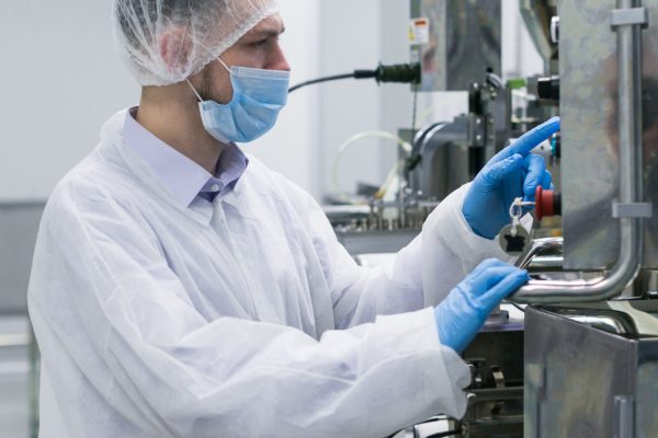 worker on factory in white suit working with manufacture machine